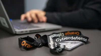 Un badge portant le nom de la société Orange Cyberdefense se trouve posé à côté d'un ordinateur portable.