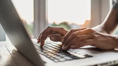 Focus on hands typing on a laptop keyboard