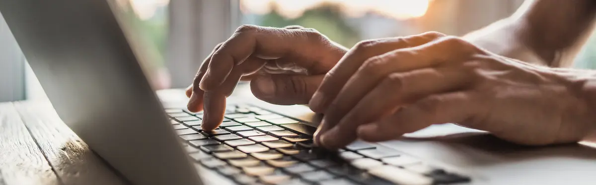 Focus on hands typing on a laptop keyboard