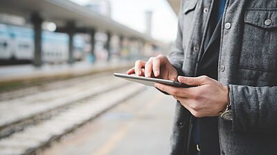 Cropped view of a man holding a smartphone at a train station