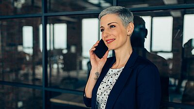 Executive standing next to a window on her mobile phone