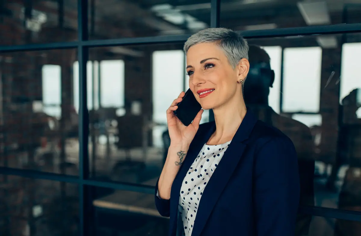 Executive standing next to a window on her mobile phone
