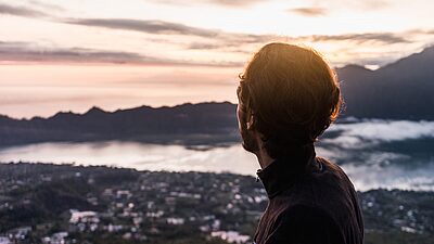 Man looking out over a city at sunset