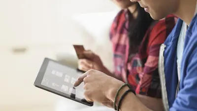 Un couple dont on aperçoit à peine le visage font leur shopping en ligne en utilisation une tablette connectée. 