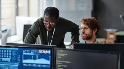 Zwei Männer arbeiten gemeinsam an einem Computer in einem Büro.