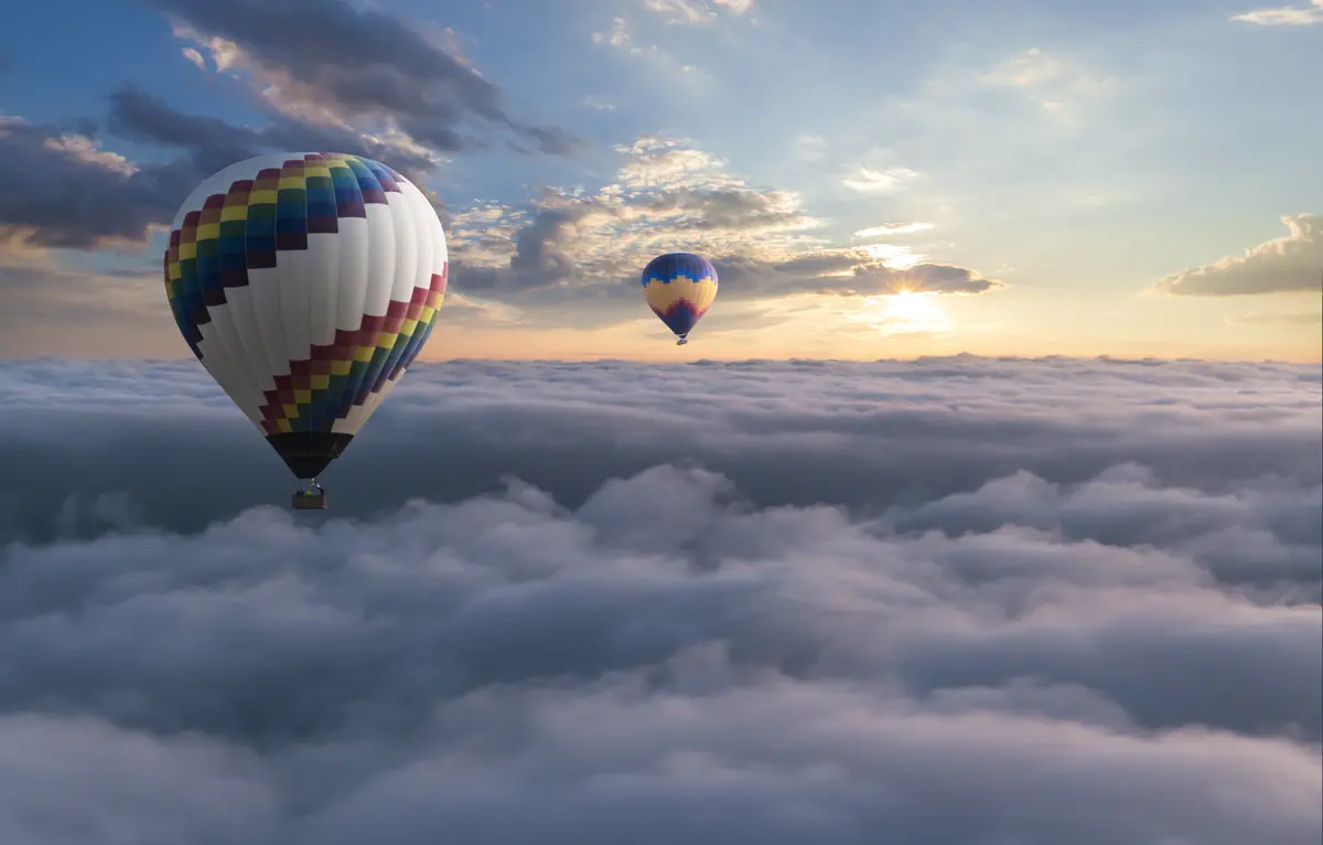 Two hot air balloons floating over the clouds
