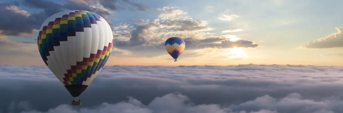Two hot air balloons floating over the clouds