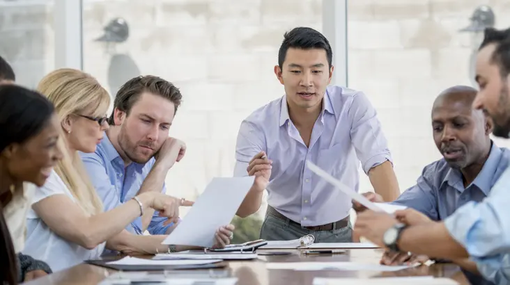 6 personnes en train d'échanger autour d'une table de réunion