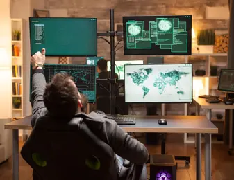A person working in a high-tech control room or cybersecurity operations center, surrounded by multiple monitors displaying global maps, data, and security information.
