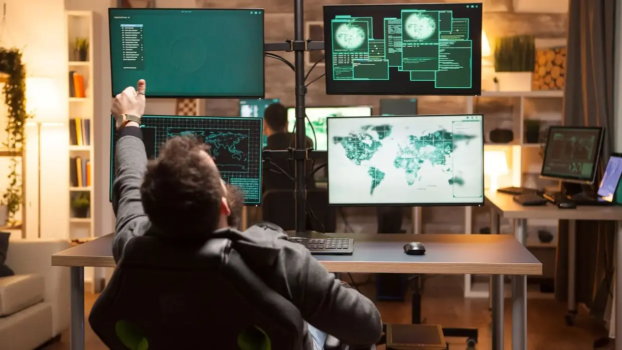 A person working in a high-tech control room or cybersecurity operations center, surrounded by multiple monitors displaying global maps, data, and security information.