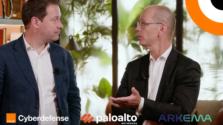 Orange Cyberdefense protège Arkema en s'appuyant sur la solution XSIAM. Deux hommes échangent en étant debout l'un à côté de l'autre.