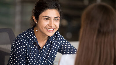 Woman seen from behind, talking to another smiling woman