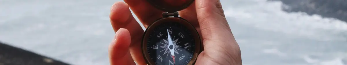 Hand holding a navigation compass outdoors