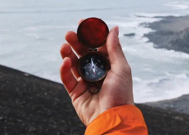 Hand holding a navigation compass outdoors