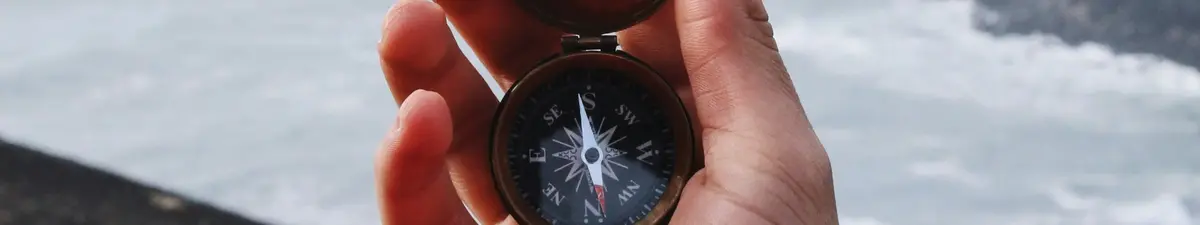 Hand holding a navigation compass outdoors