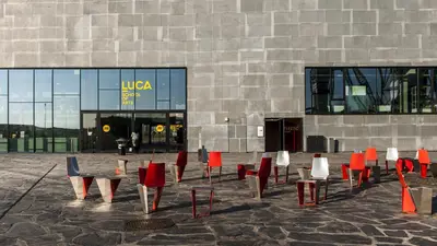 Children playing outdoors on a paved area with a modern building in the background.