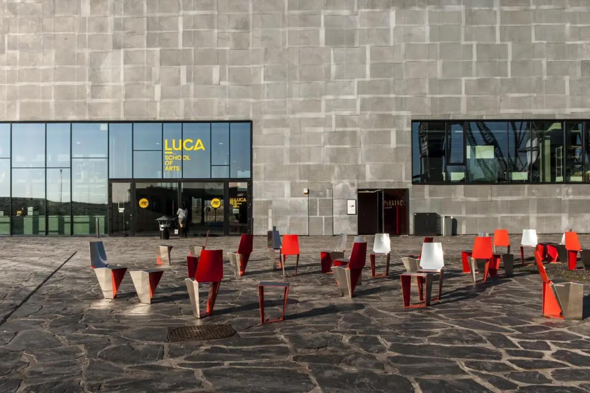 Children playing outdoors on a paved area with a modern building in the background.