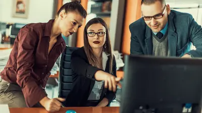 Three people huddled around a computer monitor