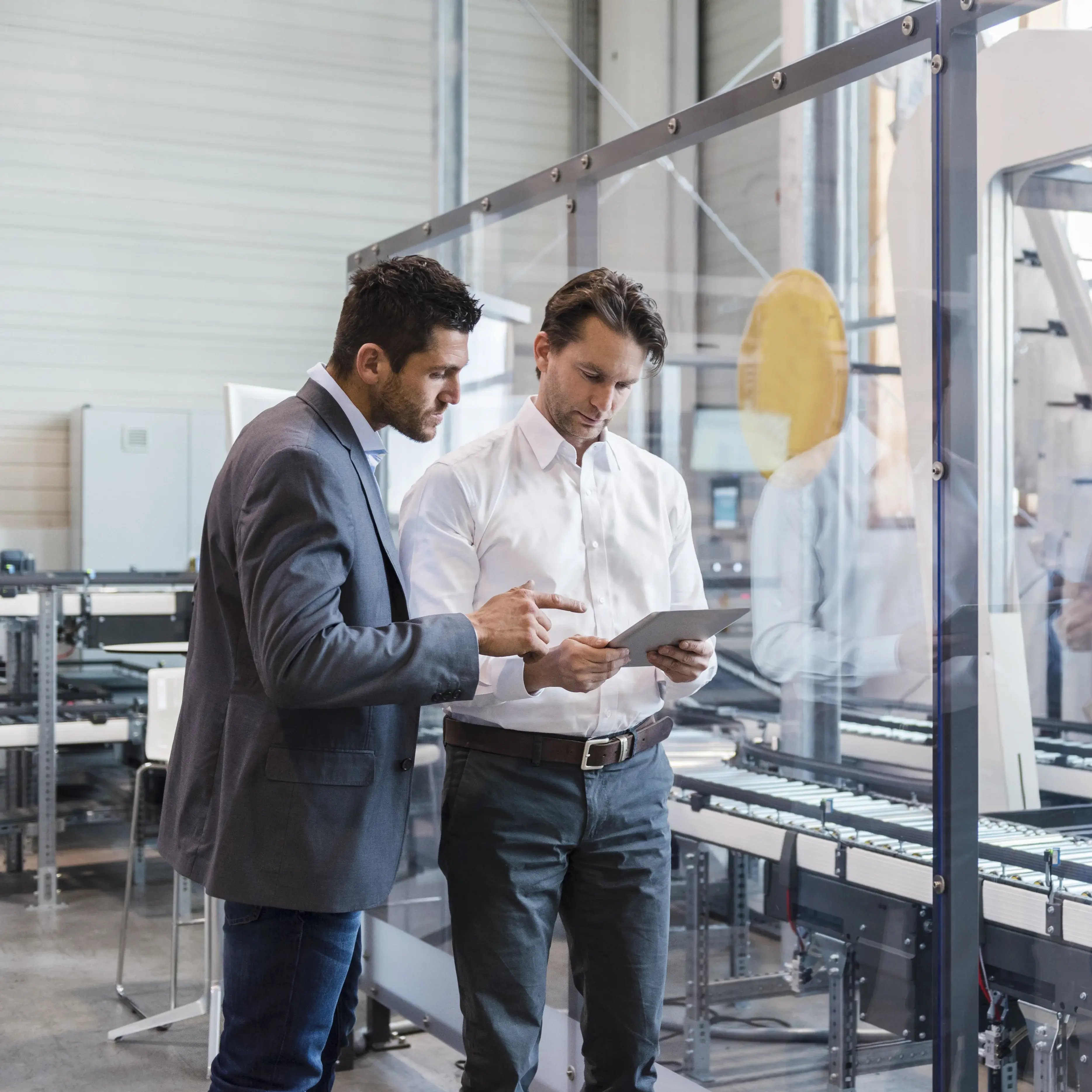 Two men looking at data on the floor of an industrial complex