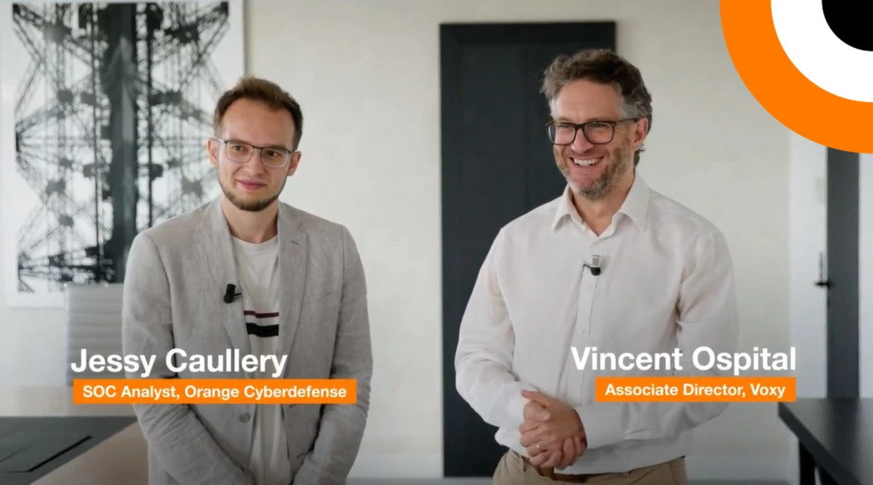 La complémentarité entre la solution Micro-SOC et la société d'infogérance Voxy.  Deux professionnels en cybersécurité se tiennent côte à côte en souriant pour les besoins d'un témoignage vidéo.