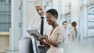 Une femme et un homme debout regardant une tablette tactile