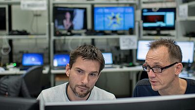 2 men in frot of a screen
