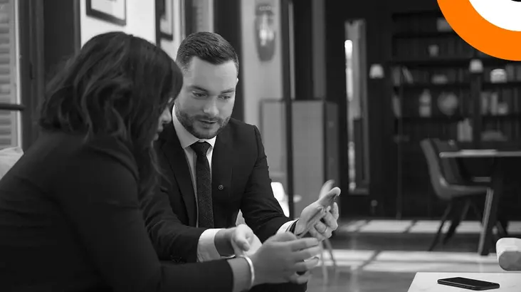 Un homme et une femme bien habillés sont assis côte à côte et regardent une tablette. 