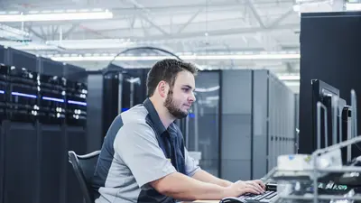 Un expert informatique travaille dans une salle de serveurs réseau. 