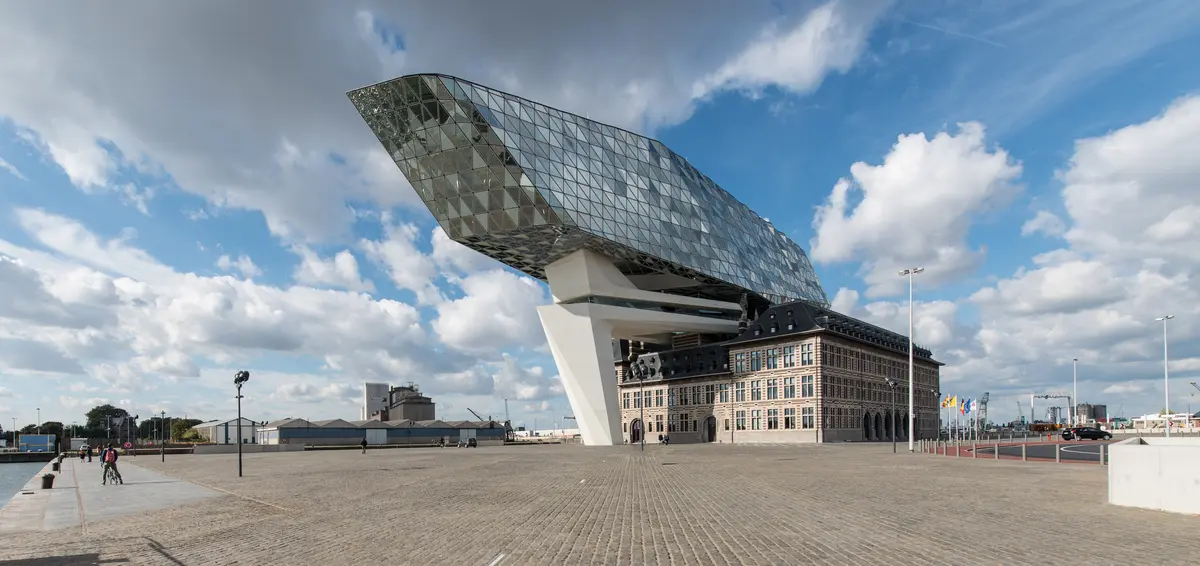 Large modern building with a unique architectural design and a sculpture in front.