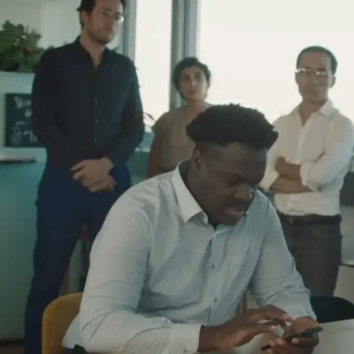 Group of four professionals standing in a meeting room, engaged in discussion.