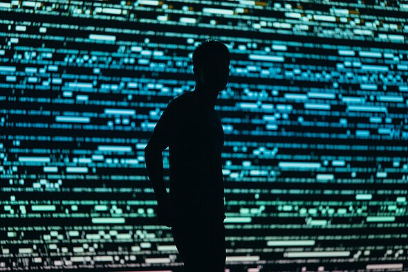 silhouette of a person standing in front of an led screen with blue lights